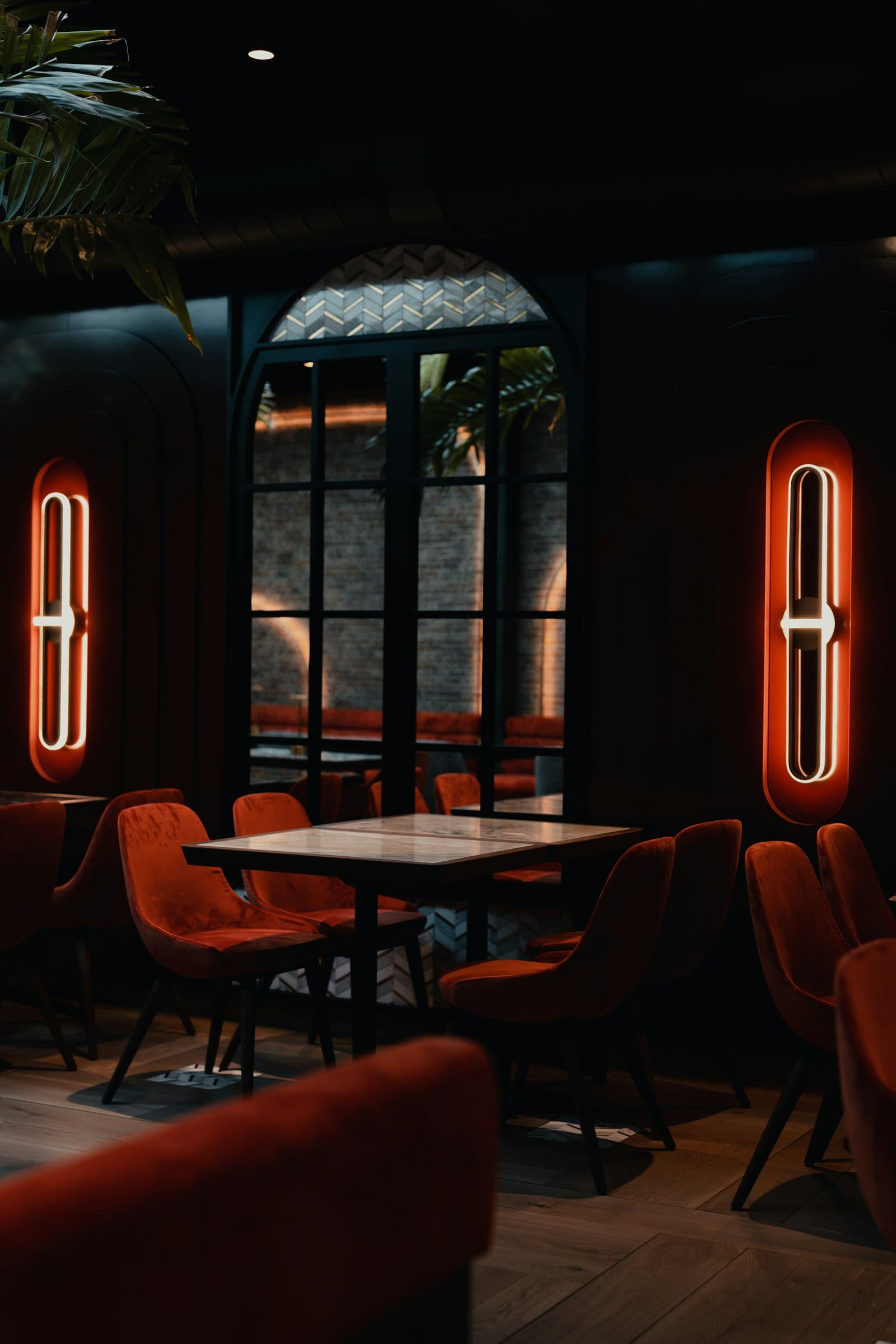 Moody restaurant interior with velvet chairs and neon wall sconces