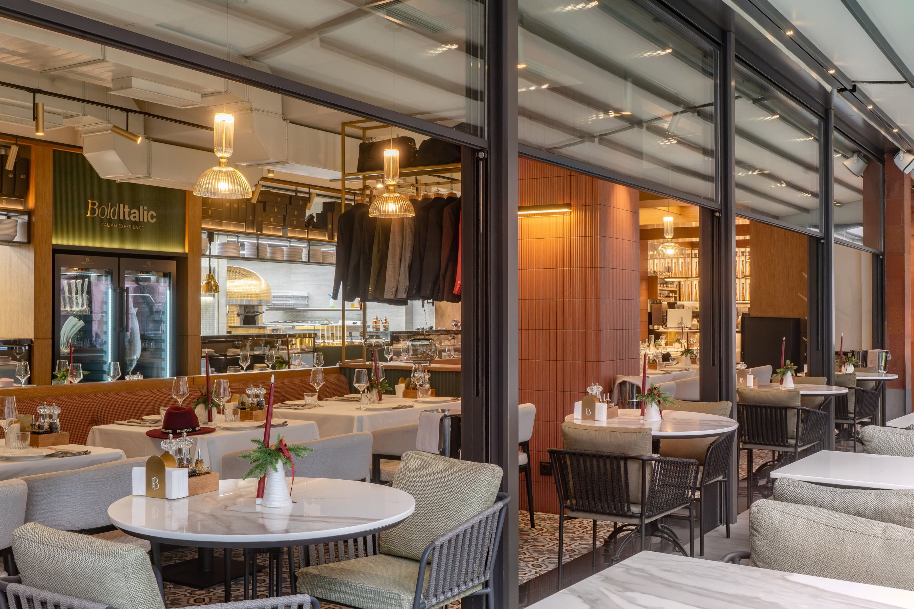 Bold Italic glass-enclosed terrace dining area with a suit rack and brass pendant lighting