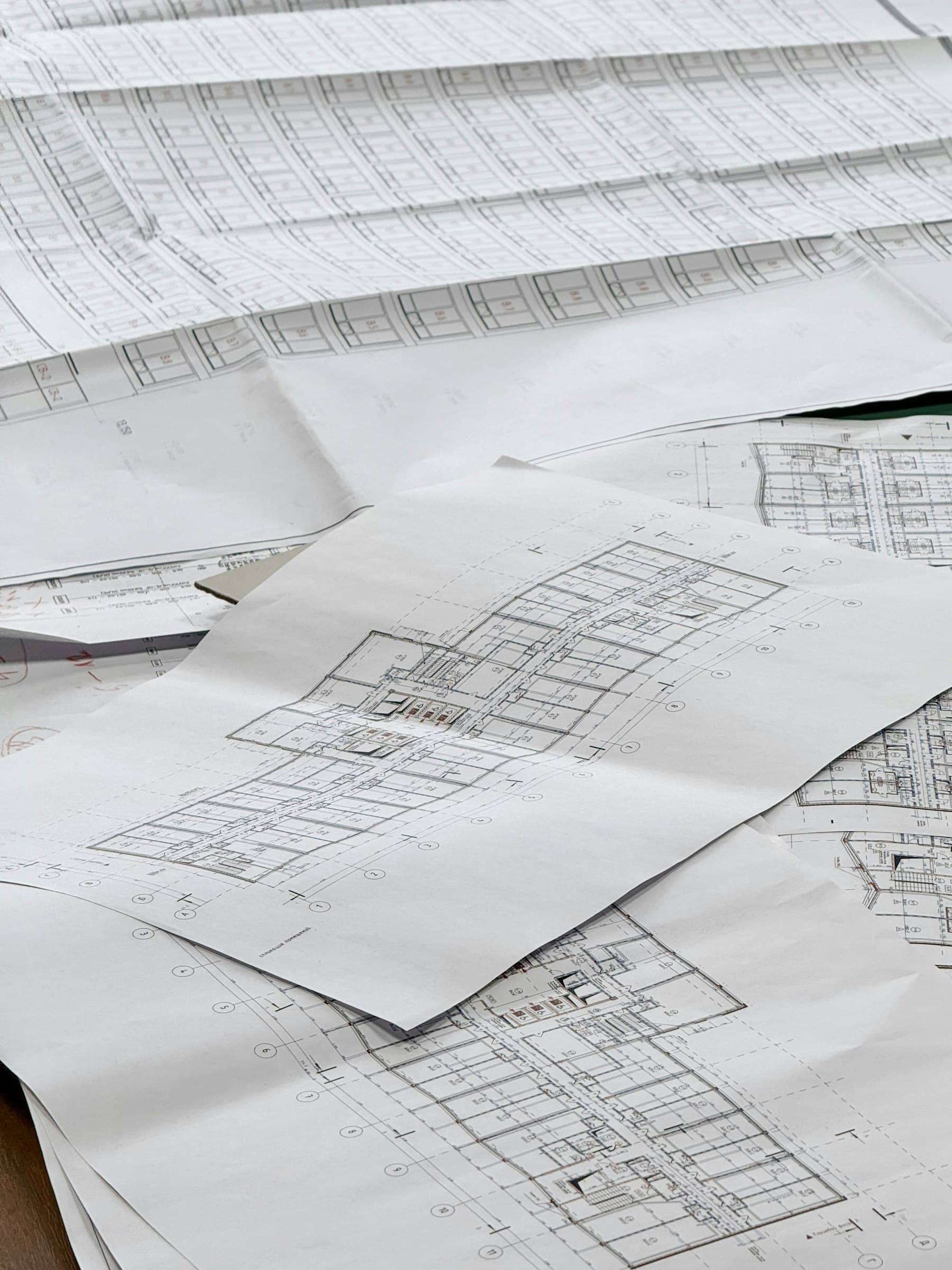 Architectural blueprints and floor plans spread across a desk