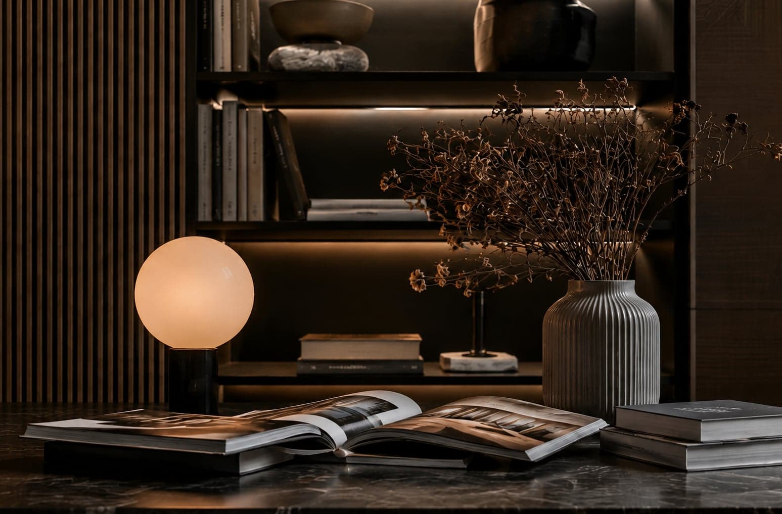 Styled reading nook with open coffee-table books, a globe lamp and dried florals